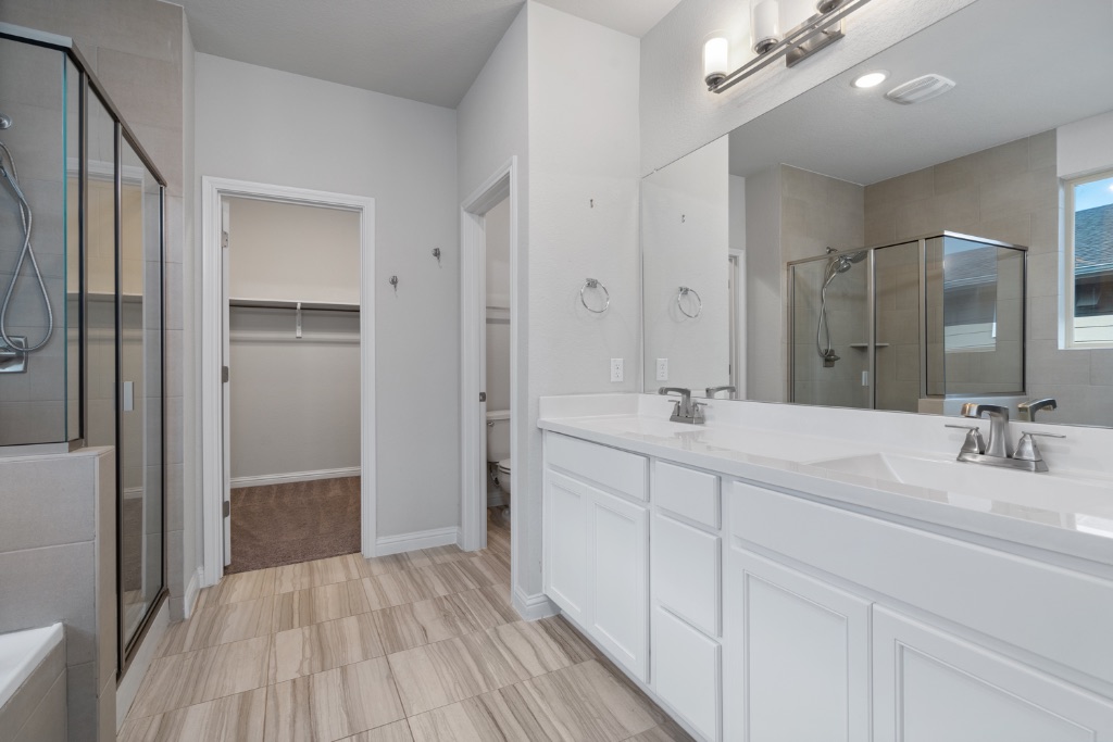 8301 Turnberry Lane Austin, TX 78744 - Photo 15 of 33 Bathroom with a shower stall, a walk in closet, and double vanity