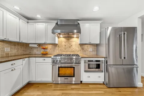 a kitchen with stainless steel appliances granite countertop a refrigerator a stove and a sink