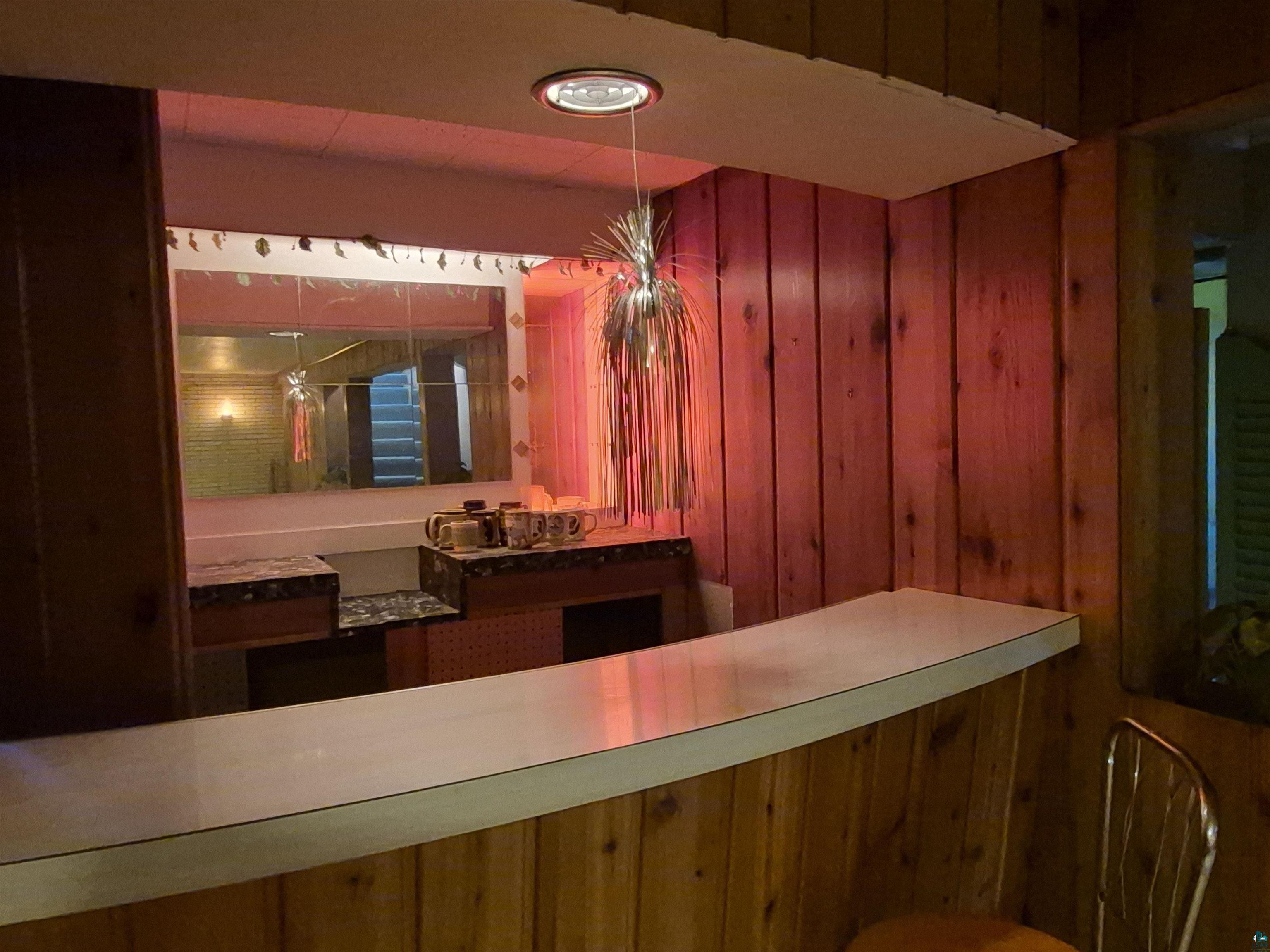 2109 West 22nd Street Duluth, MN 55811 - Photo 19 of 29 Wood-paneled bar area featuring a white countertop, built-in mirror, and marble-look surface accents