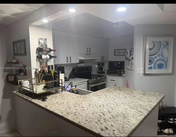 a kitchen with kitchen island granite countertop a sink stove and cabinets