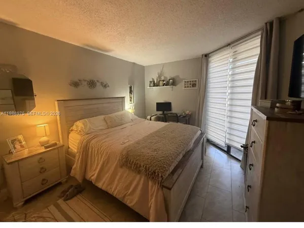 a bedroom with a bed and flat tv screen on the dresser