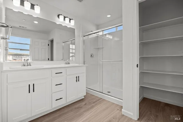 a bathroom with a double vanity sink a mirror and a shower