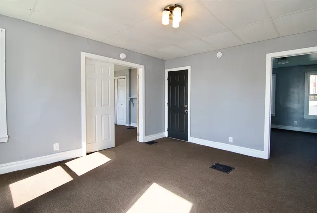 an empty room with windows and entrance to other room