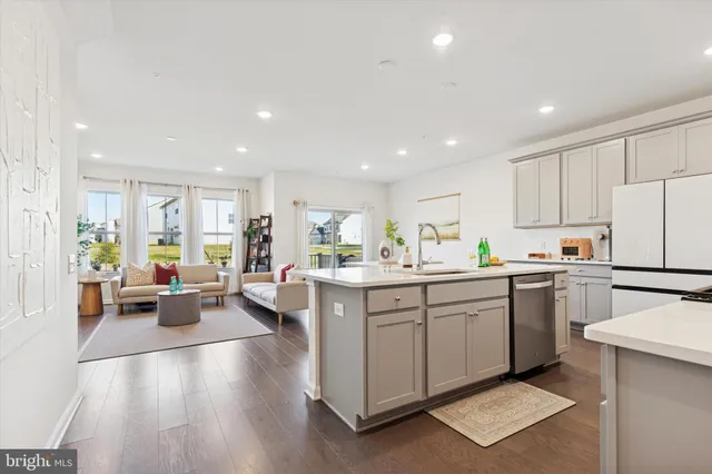a kitchen with a sink dishwasher stove and white cabinets with wooden floor
