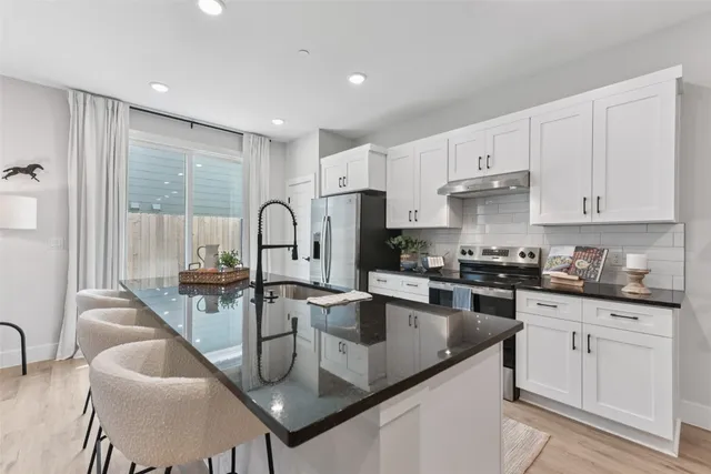 a kitchen with granite countertop a sink a stove and cabinets