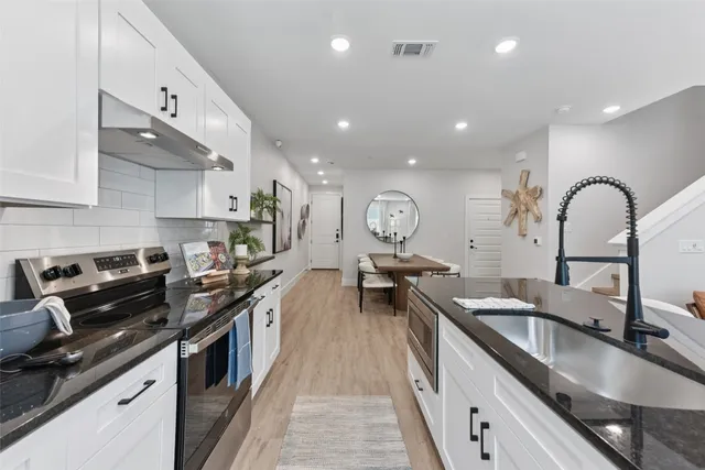 a kitchen with stainless steel appliances a sink stove and cabinets