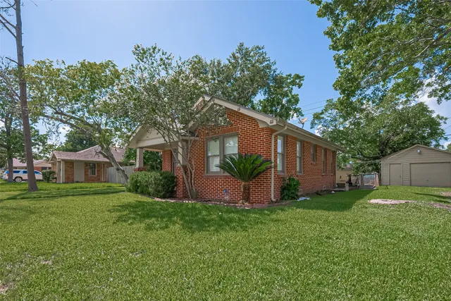 a view of a house with a yard and a large tree