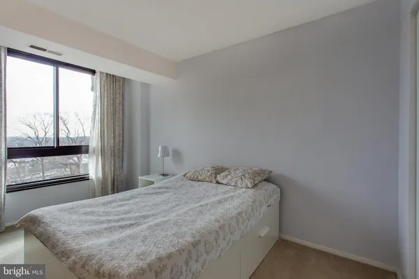 a view of a hallway with chairs and a potted plant on a table