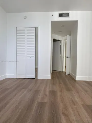 an empty room with wooden floor and closet