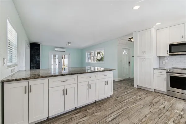 a large kitchen with granite countertop a stove top oven a sink and dishwasher with wooden floor