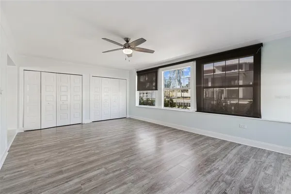 a view of an empty room with a window and wooden floor