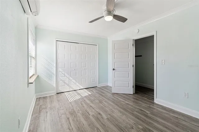 an empty room with wooden floor closet and windows