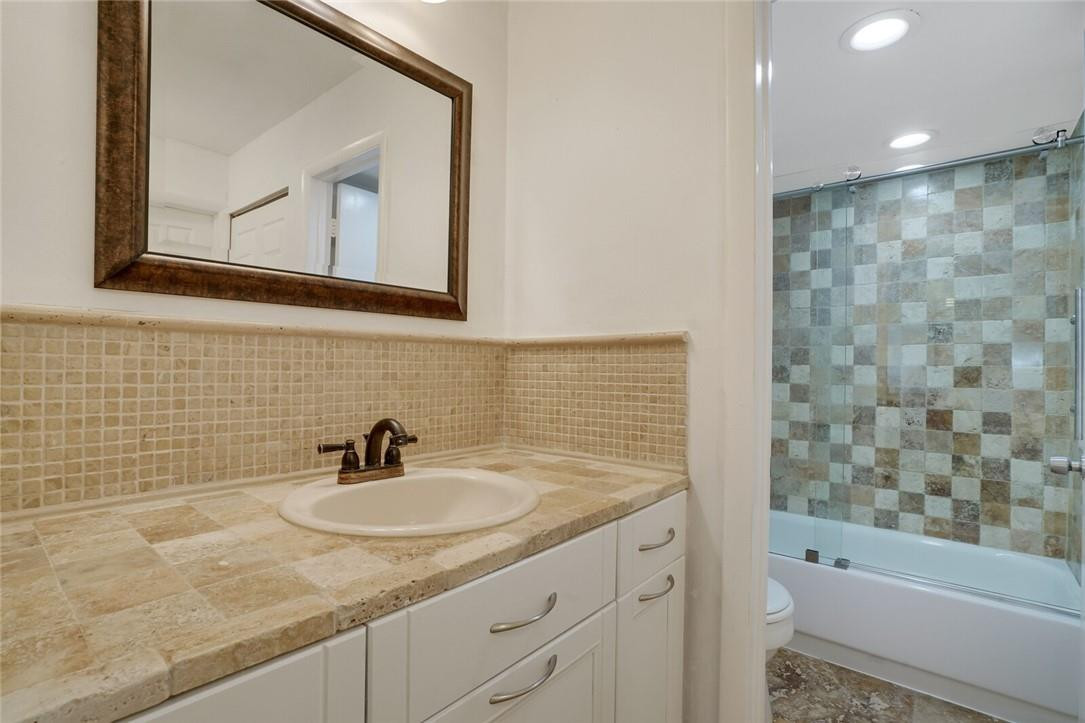 5500 Northwest 2nd Avenue, Unit 119 Boca Raton, FL 33487 - Photo 12 of 22 a bathroom with a granite countertop sink a mirror and a bathtub