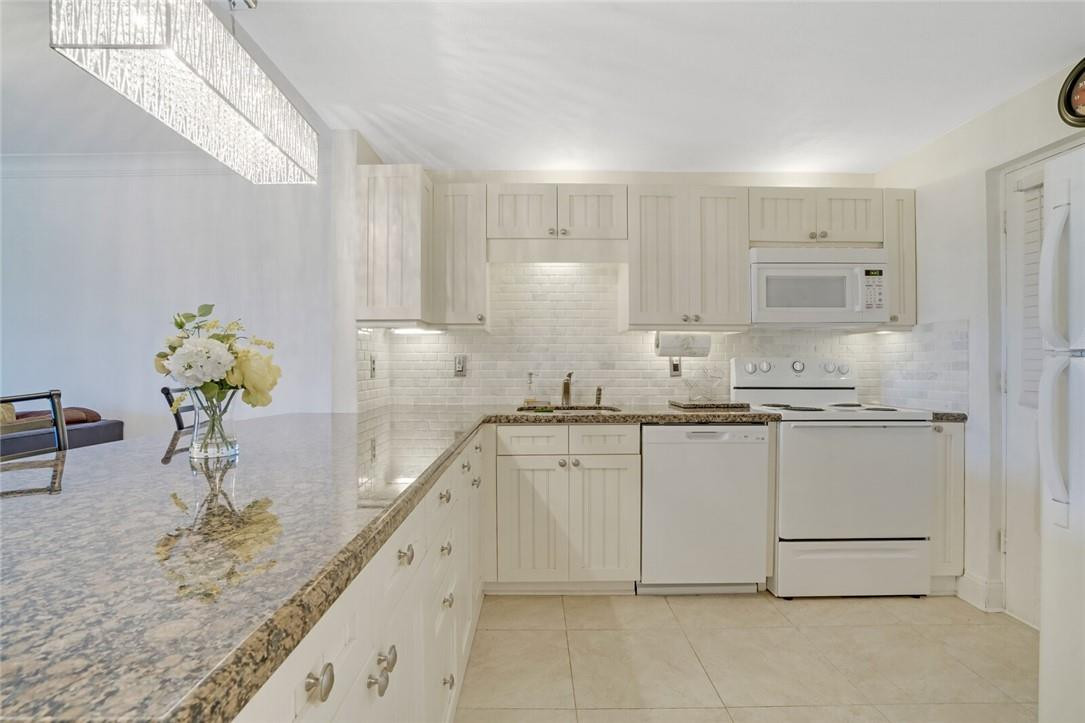 5500 Northwest 2nd Avenue, Unit 119 Boca Raton, FL 33487 - Photo 2 of 22 a kitchen with granite countertop white cabinets and white appliances
