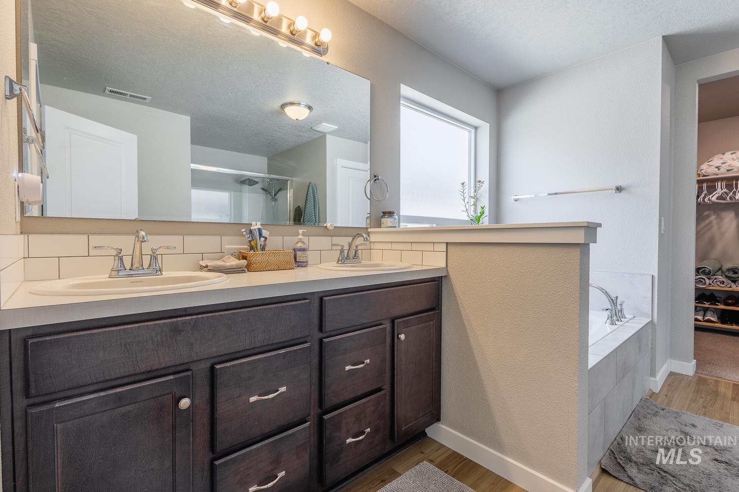 12623 Shadow Peak Street Caldwell, ID 83607 - Photo 30 of 50 Dual vanity with dark wood-finish cabinetry, chrome fixtures, and a white countertop