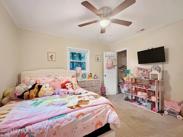 a bedroom with a bed and a flat tv screen on the dresser