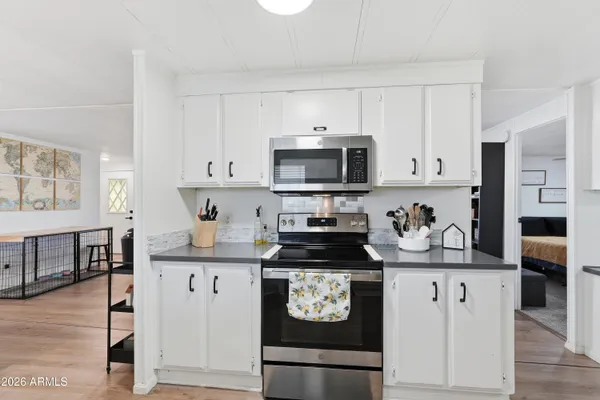 a kitchen with granite countertop a stove top oven microwave and cabinets