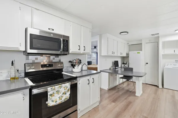a kitchen with stainless steel appliances kitchen island granite countertop a stove a sink dishwasher and a microwave with wooden floor
