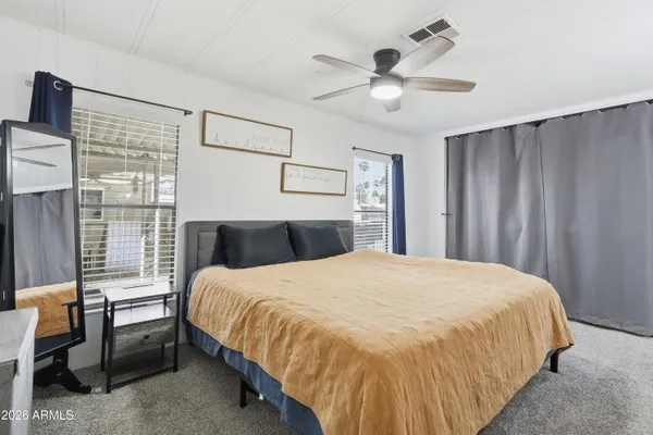a bedroom with a large bed and a chandelier fan