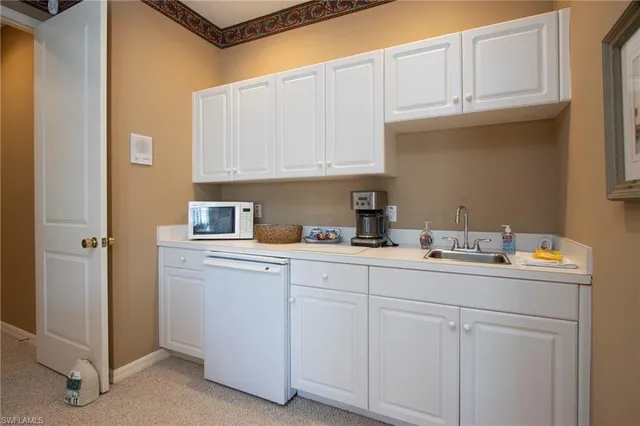a kitchen with white cabinets and sink