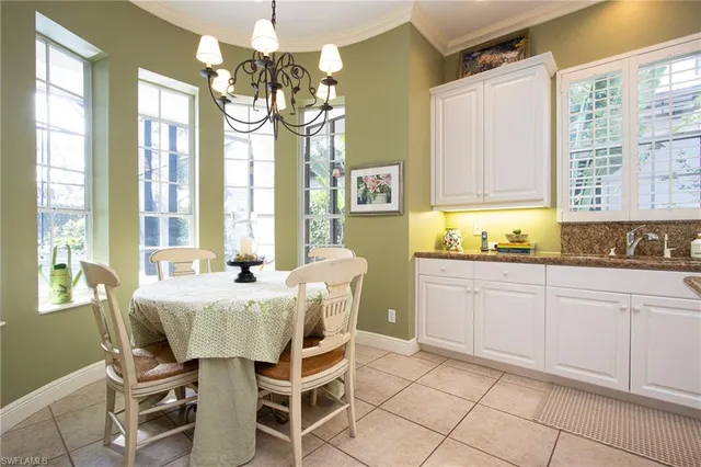 a dining hall with stainless steel appliances a chandelier and a view of kitchen