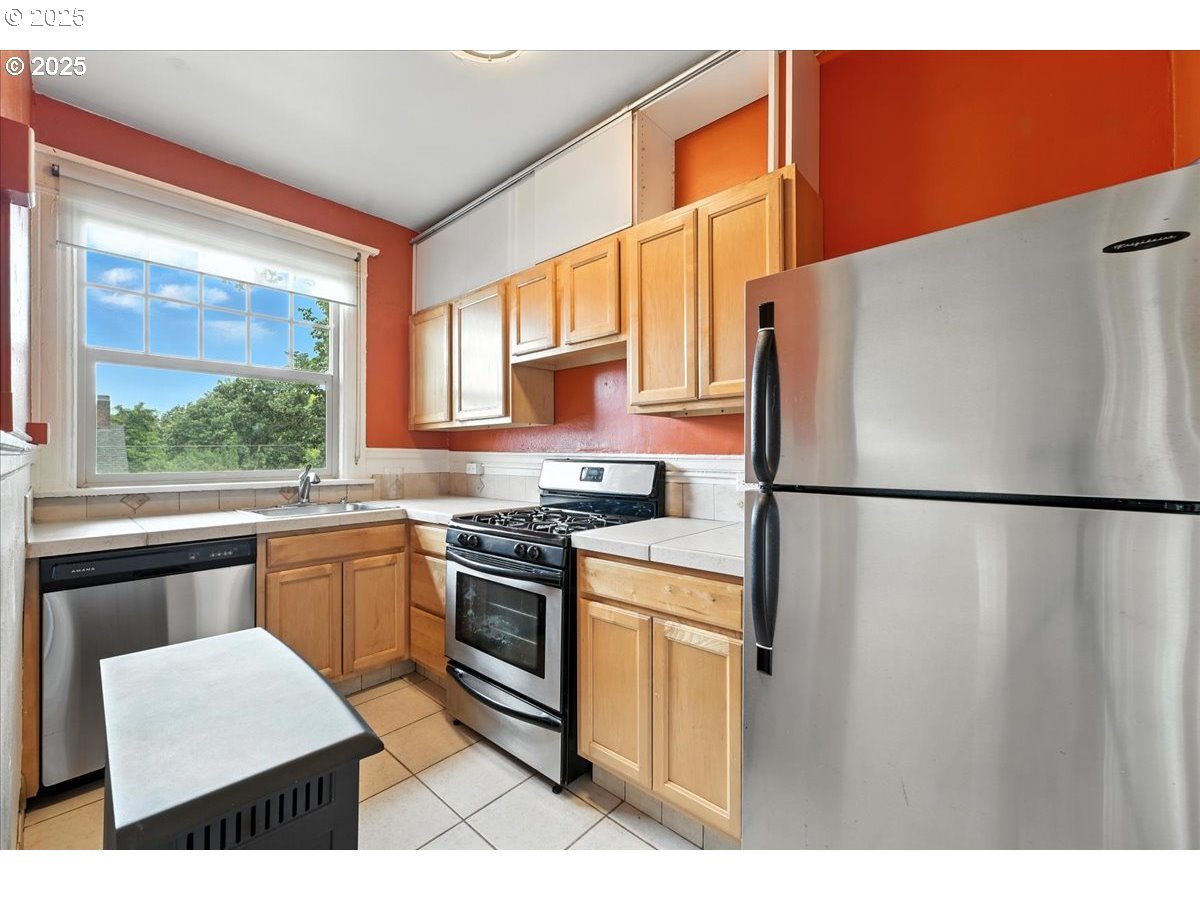2109 Northwest Irving Street, Unit 304 Portland, OR 97210 - Photo 17 of 25 a kitchen with stainless steel appliances granite countertop a refrigerator a stove a sink dishwasher and a microwave oven