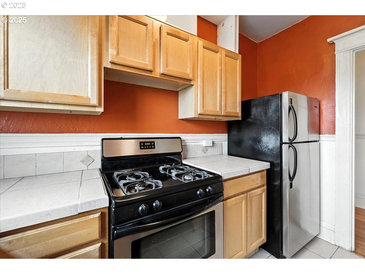 2109 Northwest Irving Street, Unit 304 Portland, OR 97210 - Photo 19 of 25 a kitchen with stainless steel appliances granite countertop a stove a refrigerator and a microwave