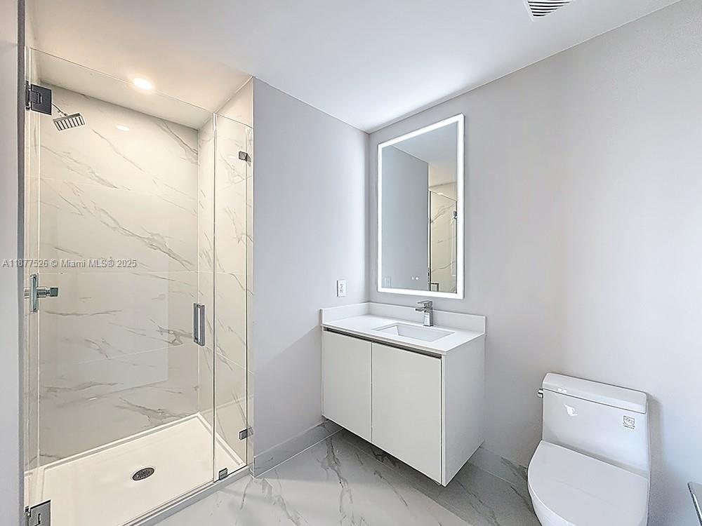 700 Northeast 24th Street, Unit 1402 Miami, FL 33137 - Photo 26 of 68 a bathroom with a granite countertop sink a toilet and shower