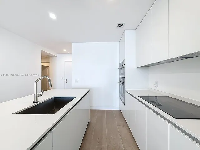 a kitchen with a sink stainless steel appliances and white cabinets