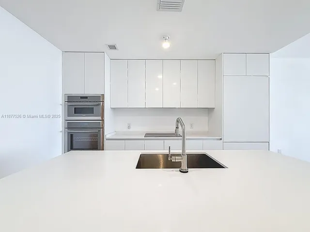 a kitchen with granite countertop white cabinets and stainless steel appliances