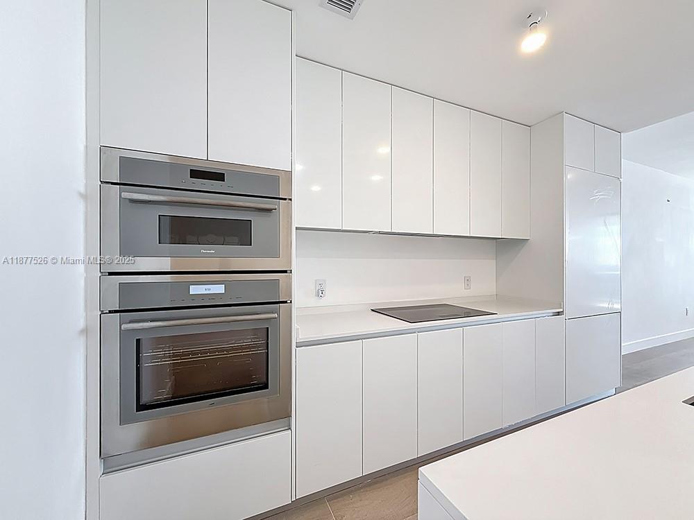 700 Northeast 24th Street, Unit 1402 Miami, FL 33137 - Photo 8 of 68 a kitchen with granite countertop white cabinets and stainless steel appliances