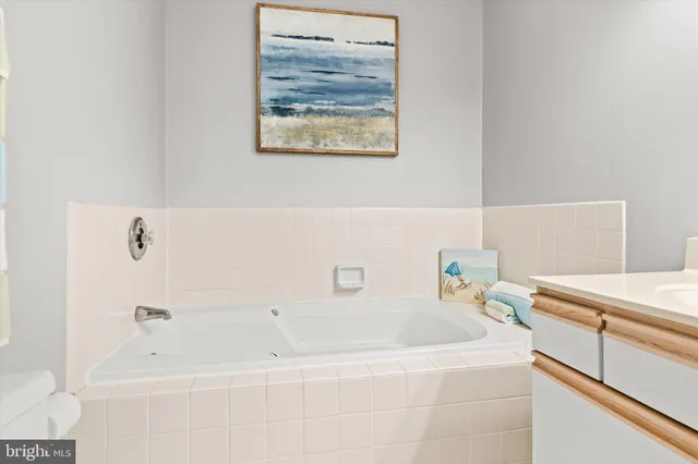 a white bath tub sitting next to a white sink and vanity