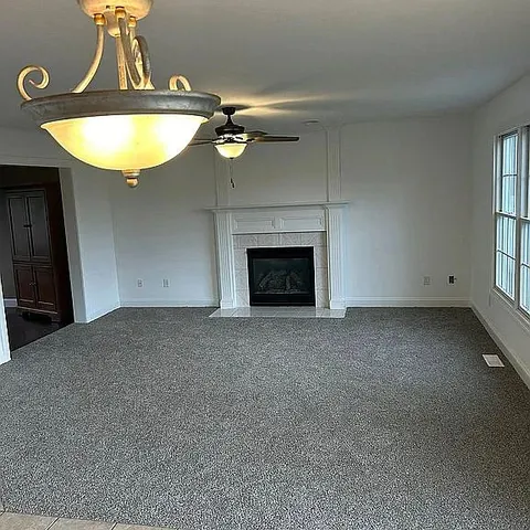 an empty room with a fireplace and chandelier