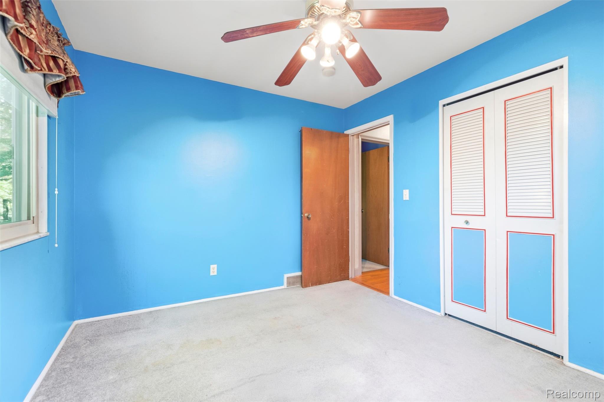 309 Windy Bluff Street Flushing, MI 48433 - Photo 16 of 32 Room featuring a window, ceiling fan with light fixture, carpeted flooring, and bi-fold closet doors