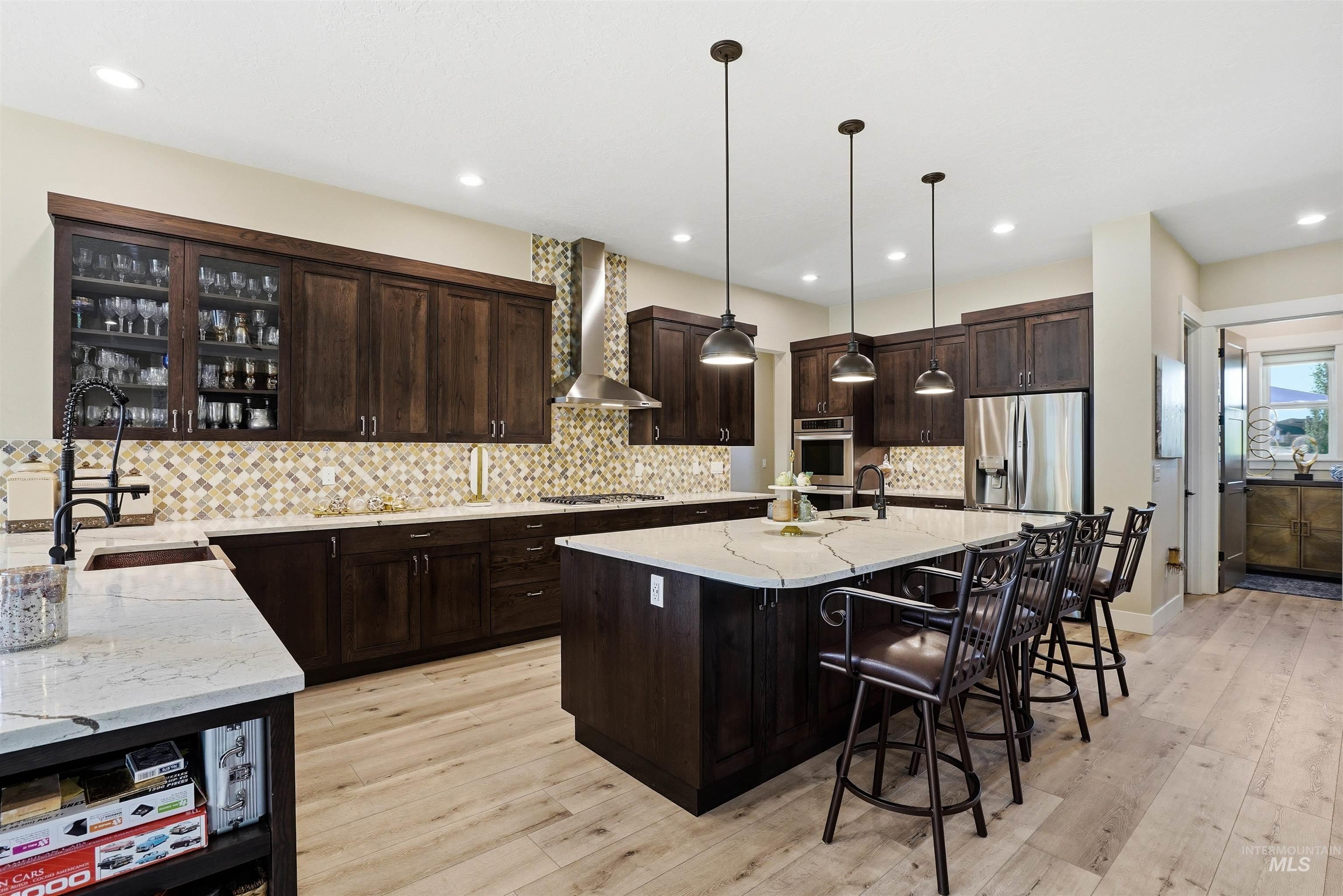 24165 Boer Goat Avenue Caldwell, ID 83607 - Photo 14 of 34 Gourmet kitchen featuring dark wood cabinetry, light wood-finish flooring, and a large central island with seating
