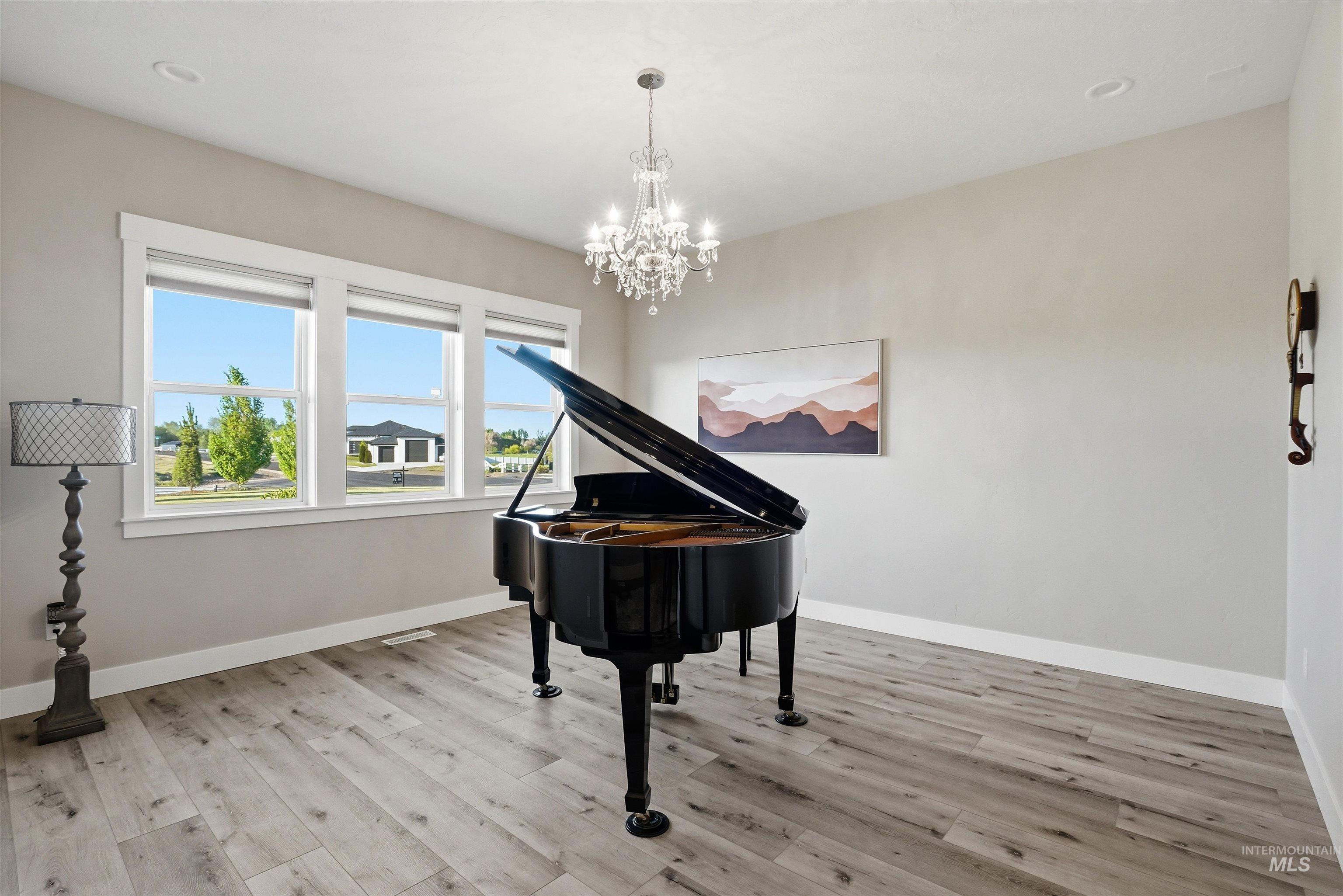 24165 Boer Goat Avenue Caldwell, ID 83607 - Photo 17 of 34 Bright room featuring wood-finish flooring, a crystal chandelier, recessed lighting, and a triple window unit with white trim