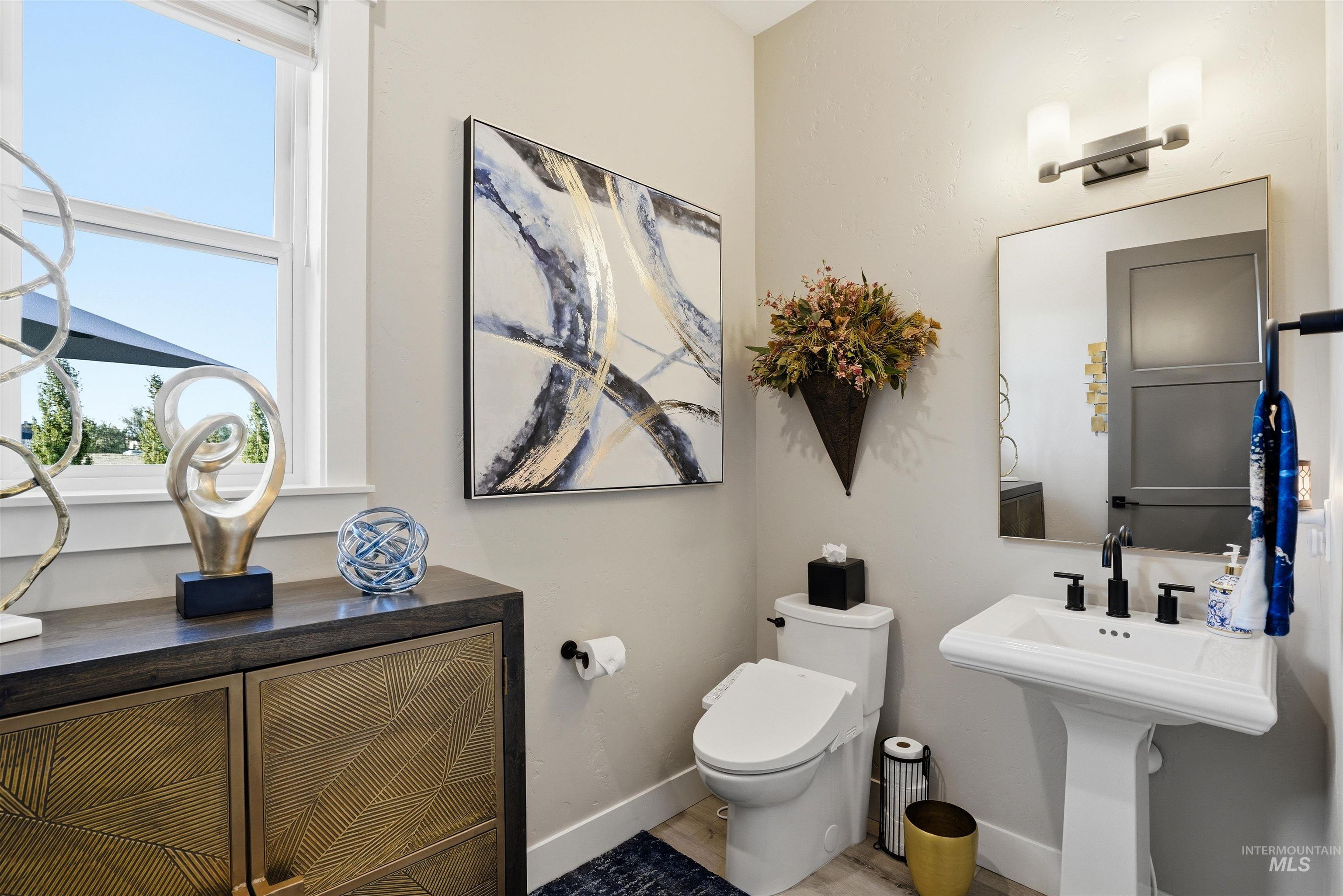 24165 Boer Goat Avenue Caldwell, ID 83607 - Photo 18 of 34 Pedestal sink with matte black fixtures, framed mirror, and a contemporary wall-mounted light fixture