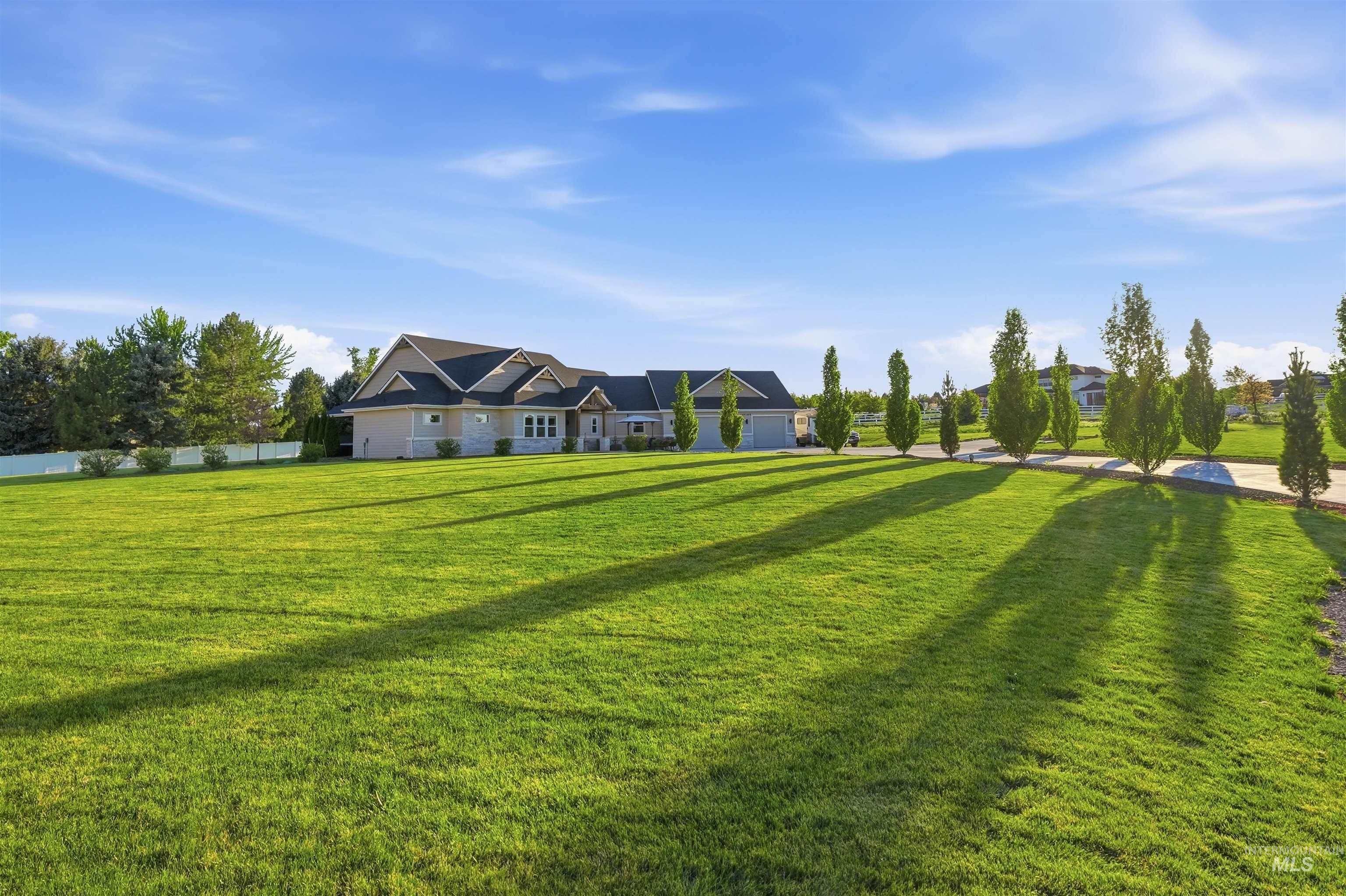 24165 Boer Goat Avenue Caldwell, ID 83607 - Photo 23 of 34 Expansive green lawn with a long asphalt driveway, bordered by a row of ornamental trees