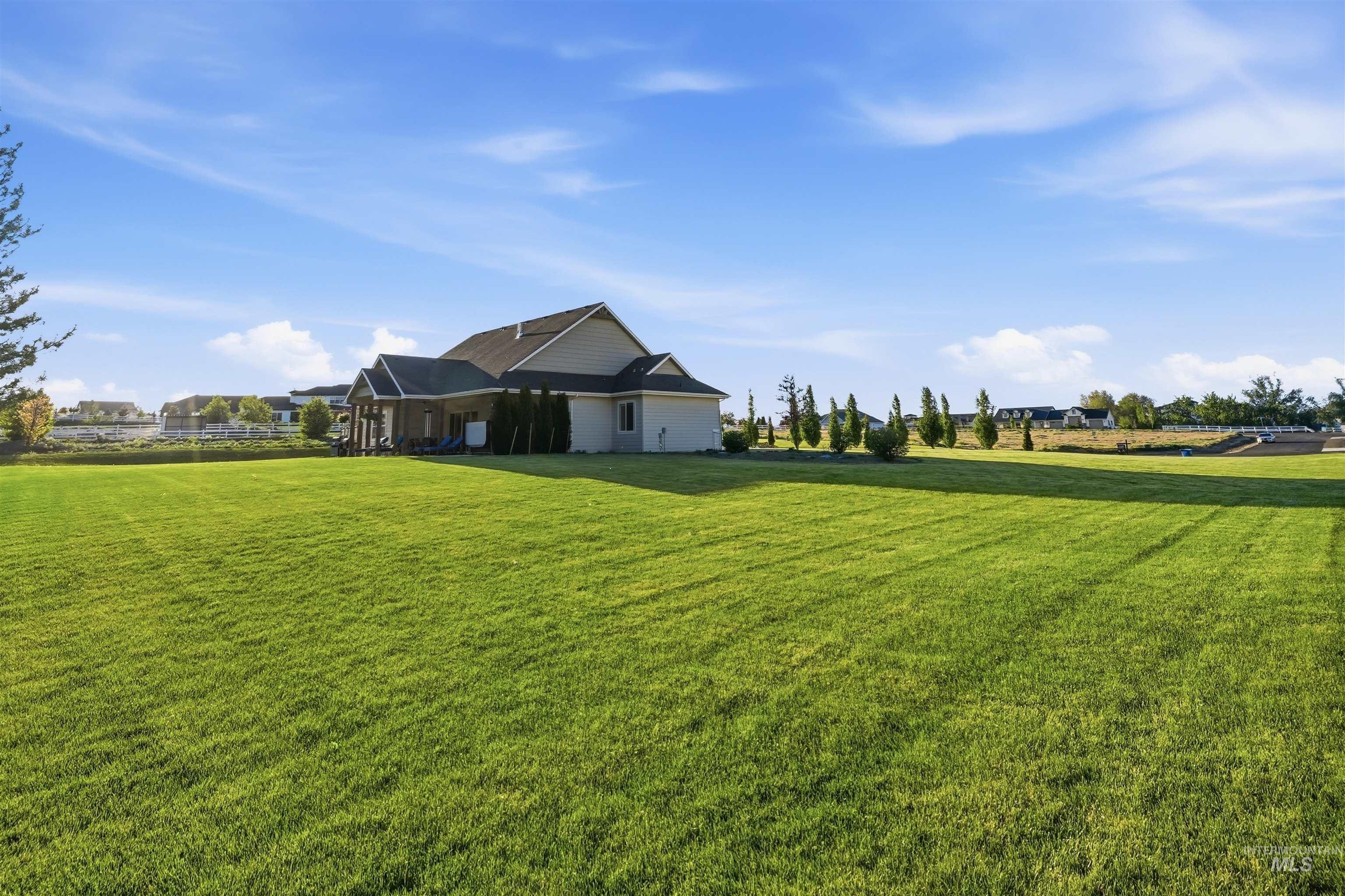 24165 Boer Goat Avenue Caldwell, ID 83607 - Photo 24 of 34 Expansive backyard featuring a manicured lawn, covered patio, and mature landscaping