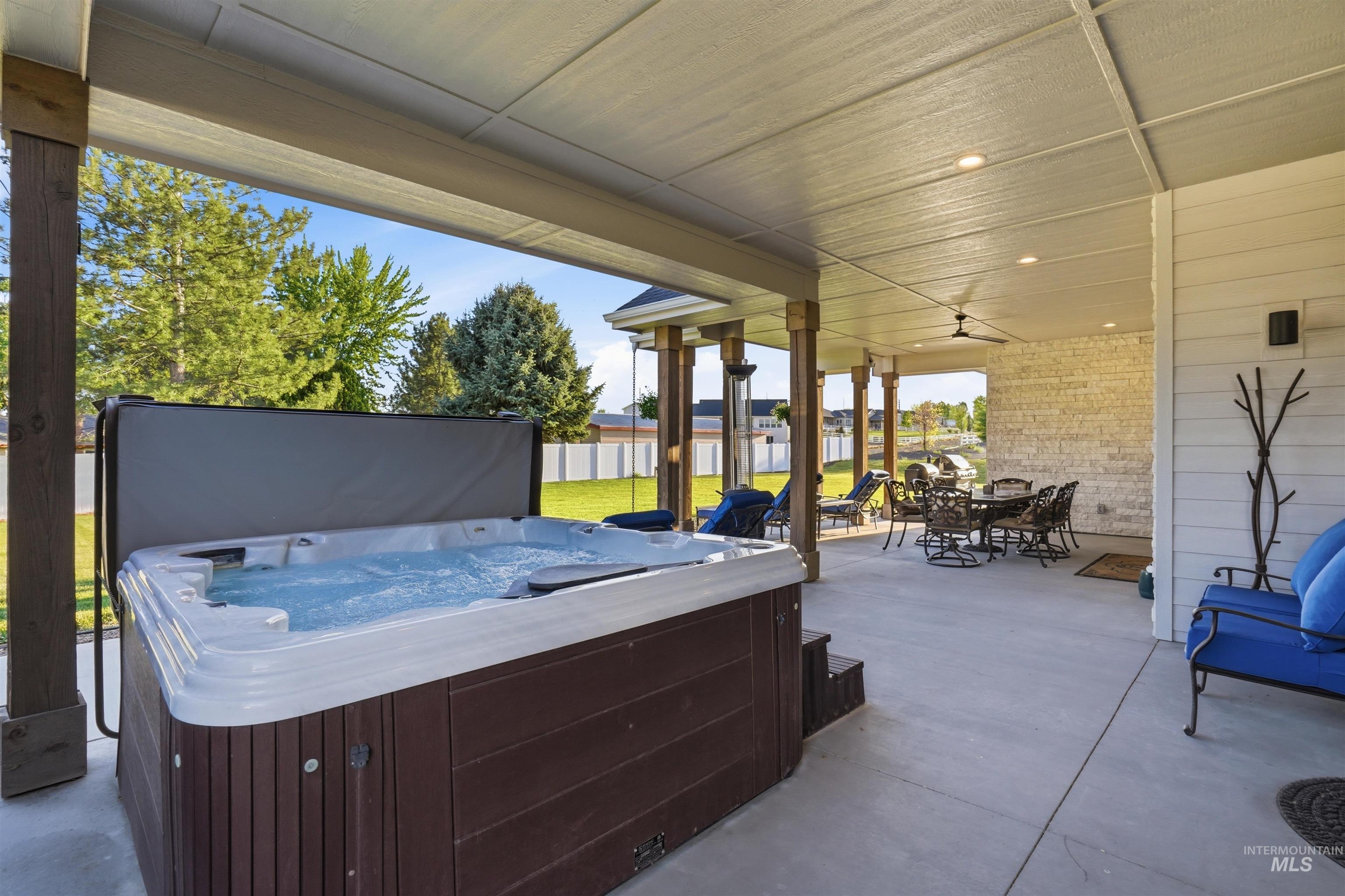 24165 Boer Goat Avenue Caldwell, ID 83607 - Photo 28 of 34 Covered patio featuring an active hot tub, concrete flooring, recessed lighting, ceiling fan, and a stone accent wall