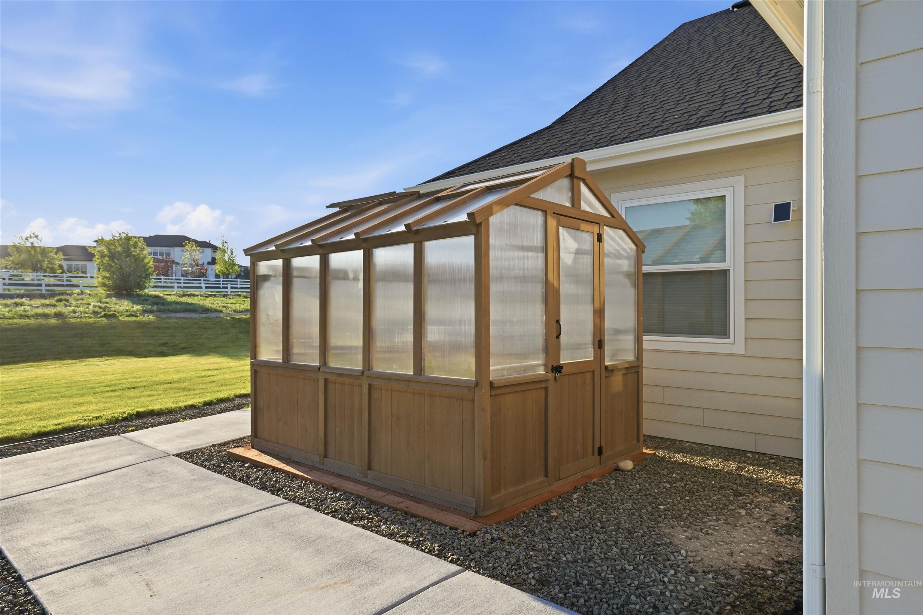24165 Boer Goat Avenue Caldwell, ID 83607 - Photo 29 of 34 Wood-frame greenhouse featuring clear paneling, double doors, and a sloped roof design