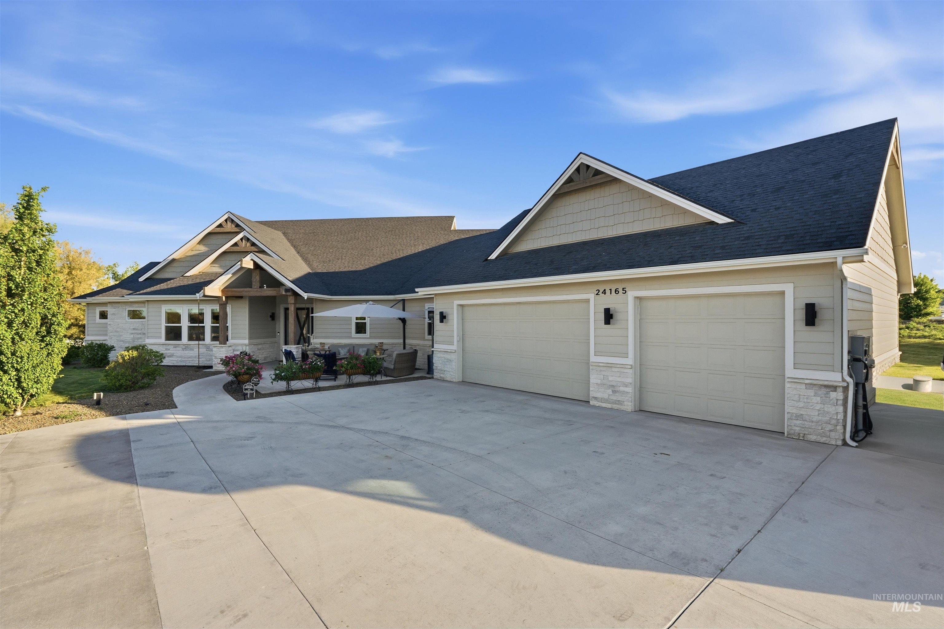 24165 Boer Goat Avenue Caldwell, ID 83607 - Photo 34 of 34 Ranch-style exterior with a three-car garage, stone accents, decorative timber framing, and a large concrete driveway