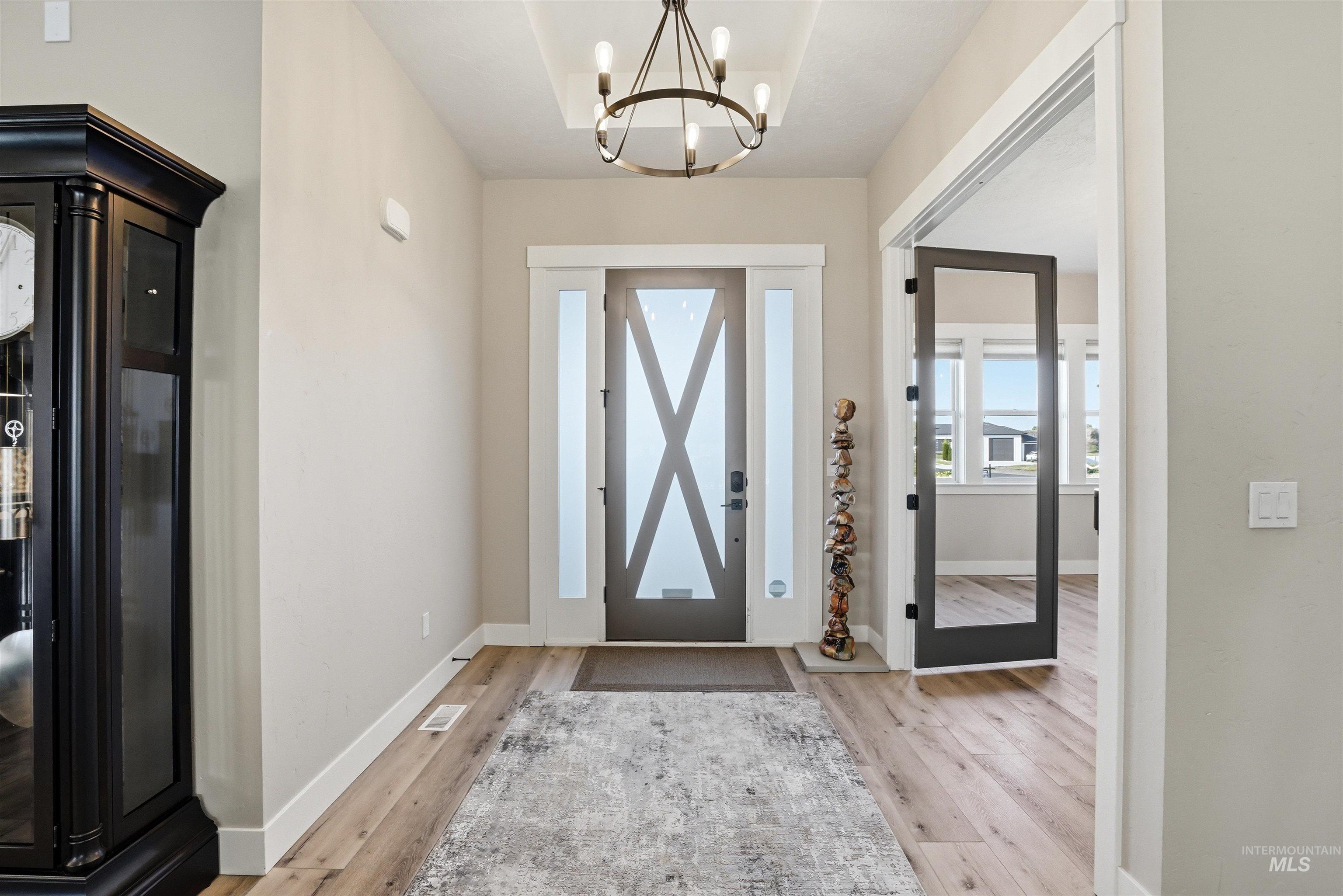 24165 Boer Goat Avenue Caldwell, ID 83607 - Photo 5 of 34 Entryway with wood-finish flooring, a contemporary chandelier, and a transom window above the front door