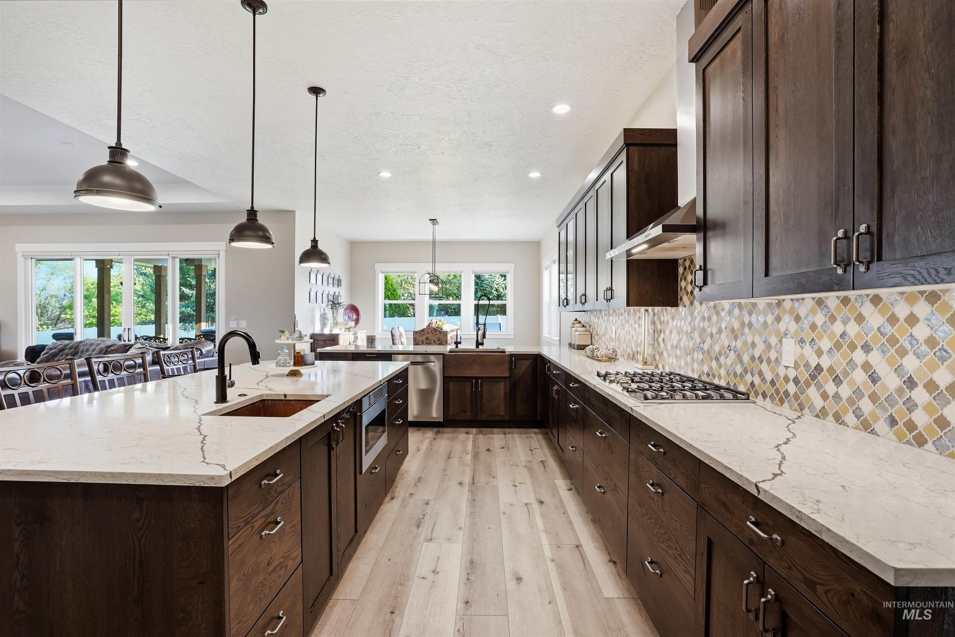24165 Boer Goat Avenue Caldwell, ID 83607 - Photo 10 of 34 Kitchen featuring dark wood cabinetry, light wood-finish flooring, white countertops, and a patterned tile backsplash