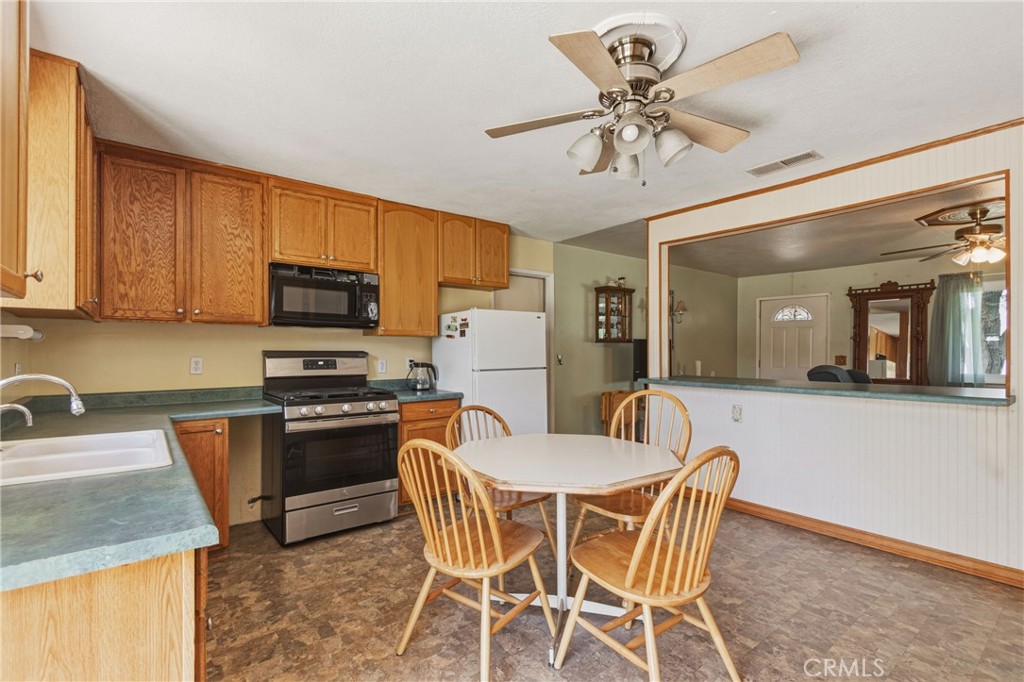 6812 Helton Street Winton, CA 95388 - Photo 9 of 24 a kitchen with stainless steel appliances granite countertop a stove top oven a sink a dining table and chairs with wooden floor