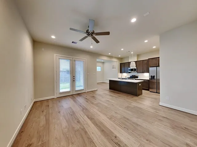a view of empty room with wooden floor and fan