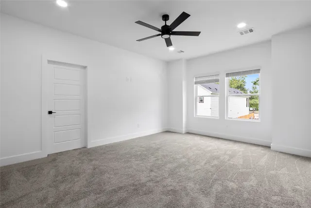 an empty room with windows and ceiling fan