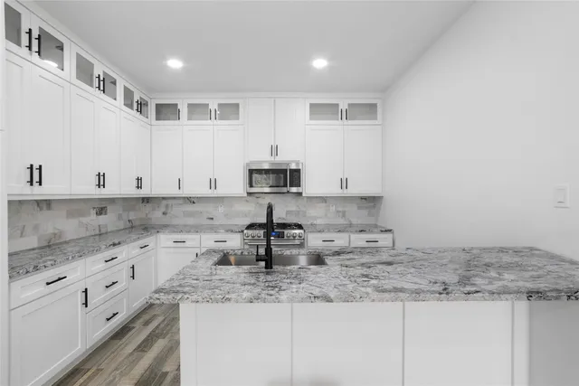 a kitchen with granite countertop a sink a stove and cabinets