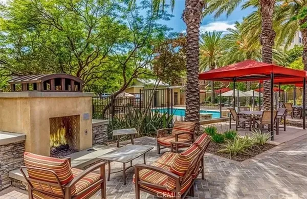 a view of a patio with couches table and chairs under an umbrella with a fire pit