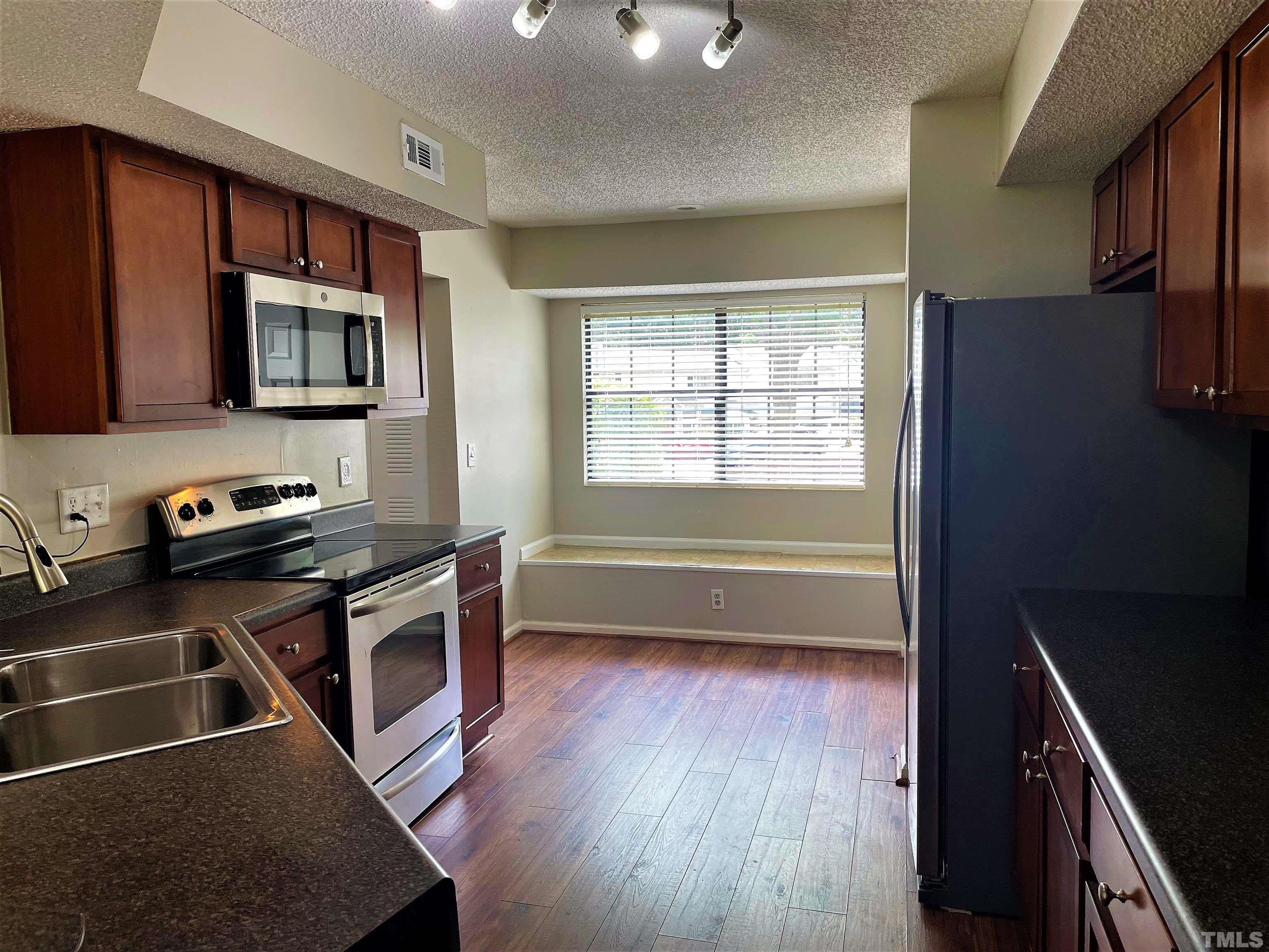 2416 Condor Court Raleigh, NC 27615 - Photo 4 of 28 a kitchen that has a microwave a stove and a cabinets